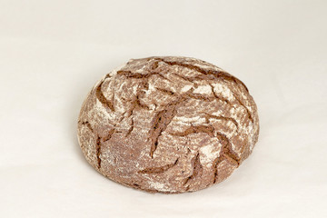 Gray round loaf of rye bread, an assortment of bread and bakery products. Closeup on a light background