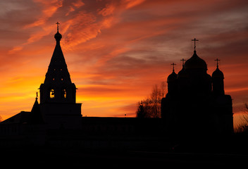 The black silhouette of the monastery against the background of a bright multicolored sunset.