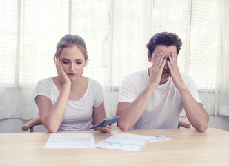Young caucasian couple hand holding credit card and debt bill on table in home,men and women have...
