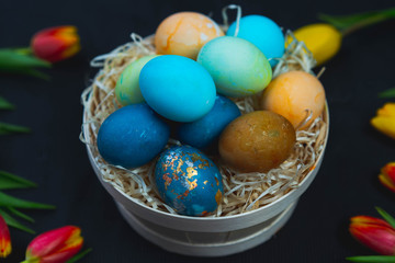 basket with Easter eggs on the table, yellow and red tulips, spring, holiday.