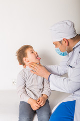 Obraz premium Children's doctor examining little patient's throat in clinic