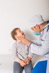 Children's doctor examining little patient's throat in clinic
