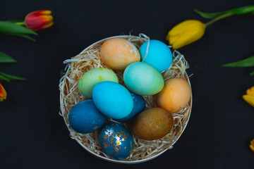basket with Easter eggs on the table, yellow and red tulips, spring, holiday.