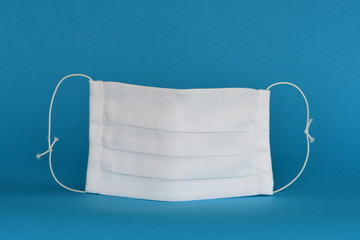  Handmade fabric reusable medical face mask isolated on blue background.