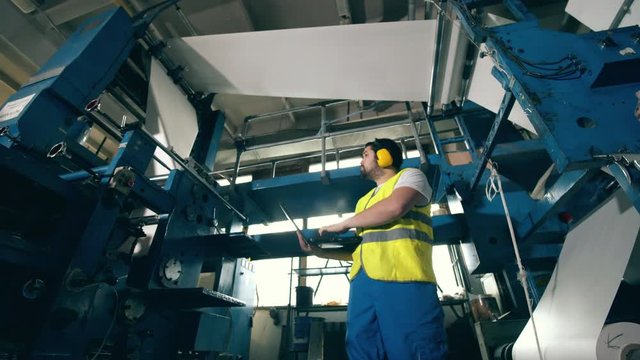 Factory inspector is observing paper rolling through the equipment