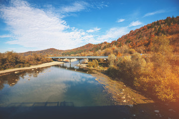 Panoramic view of mountain valley with river and bridge in autumn.