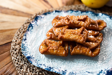 Traditional sweets of Spanish gastronomy on rustic wooden table and polka dot plate (Pestiños)