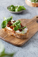 Fototapeta na wymiar Sandwich on toast with fresh radish microgreen and cream cheese on grey background. Close up.
