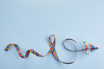 Autism awareness day or month. Paper plane in origami style with autism awareness puzzle ribbon on blue background.