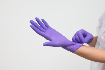 Woman doctor putting blue latex medical gloves on white background.Surgeon wearing gloves before surgery at operating room.Risk and infection control concept.