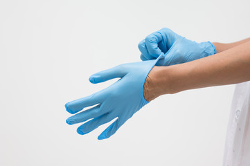 Woman doctor putting blue latex medical gloves on white background.Surgeon wearing gloves before surgery at operating room.Risk and infection control concept.
