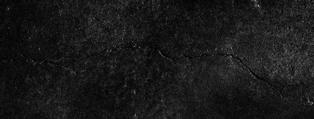 Black background of a texture of cement, stone and concrete with a crack - Dark stage background - Large panoramic format