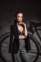 Attractive tanned brunette model in sexy lingerie, men's jacket posing against bike Shadow. Sexy girl with beautiful makeup. bike advertising concept.