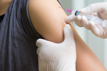 close up doctor's hand injecting for vaccination in the shoulder woman patient.Vaccine for protection HPV (Human Papillomavirus) infection.Vaccination for coronavirus treatment.