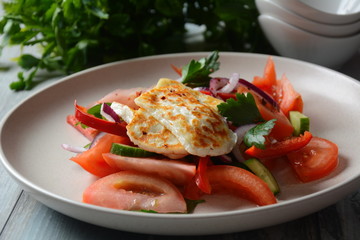 Grilled Halloumi Cheese salad with tomatoes, cucumbers, red pepper, red onion. Healthy vegeterian food. Keto diet.