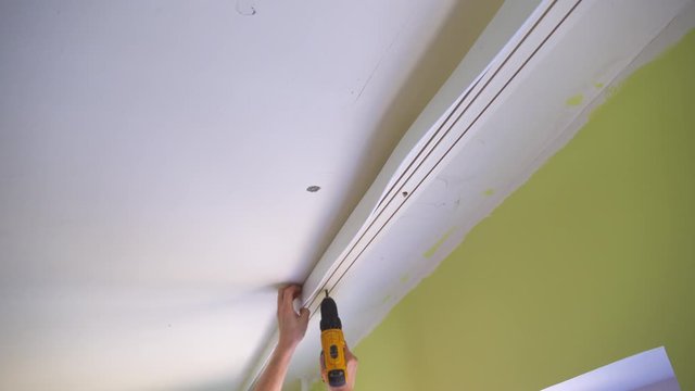 the master dismantles the cornice, holder for curtains, for installing suspended ceilings.