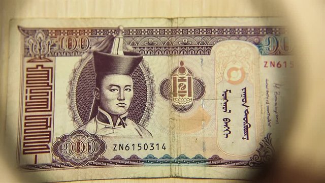 View a One hundred Mongolian tugriks bill lying on a table with a magnifying glass. concept of business and finance.