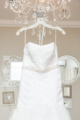 Hanging white wedding dress with a wall of mirrors in the background