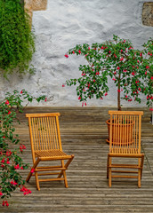 Obraz premium two chairs at terrace with fuchsia plant pots