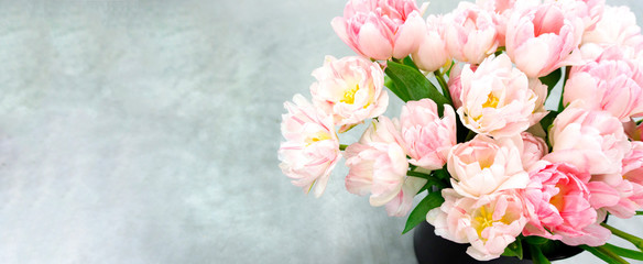 An elegant card with a bouquet of pink tulips on a light gray background with  copy space for congratulatory text and wishes. A luxurious bouquet of tulips as a gift for Easter, mother's day, wedding.