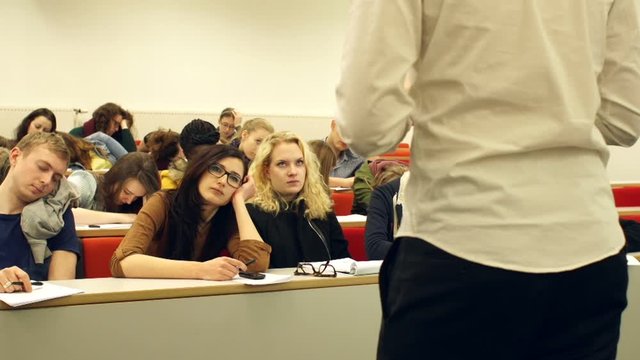 College Students sleeping or asleep in class in a University Lecture Hall or Classroom while someone is speaking. Stock Video Clip Footage