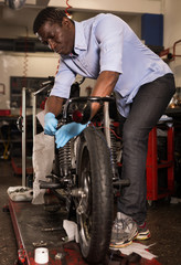 Afro american worker fixing failed motorcycle in workshop
