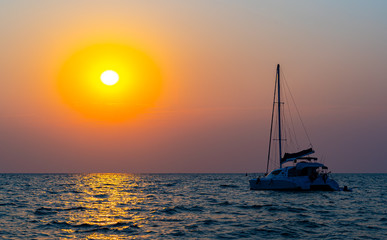 Naklejka na ściany i meble Sunset views at the sea with a yacht