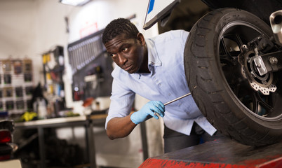 Afro american expert inspects the wheel of a motorcycle