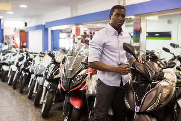 Portrait of adult man buying new motorcycle at modern showroom