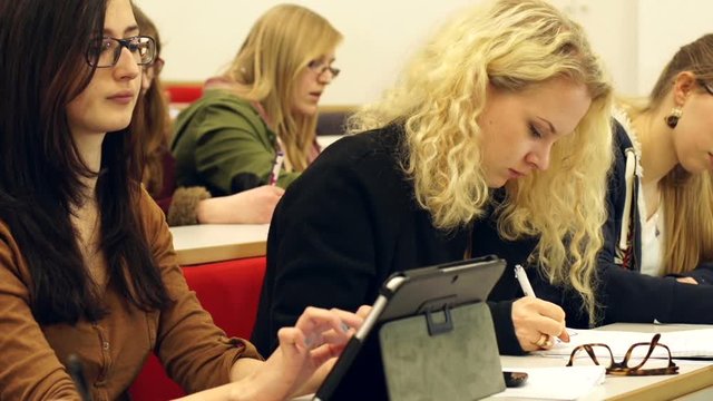 College Students using a Digital Tablet in a University Lecture Hall or Classroom. The group of people are taking notes. Tracking Shot. Stock Video Clip Footage