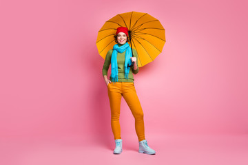 Full size photo of cheerful girl hold her bright yellow parasol enjoy season free time trip wear jumper trousers shoes isolated over pink color background