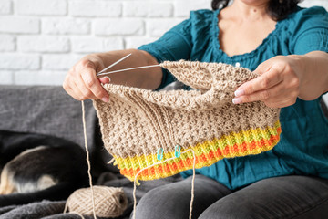 middle aged woman enjoying being at home and knitting sitting on the sofa