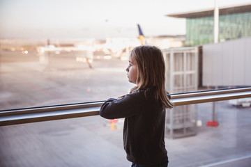 Naklejka premium Little girls is looking to airplans in airport waiting lounge in Budapest