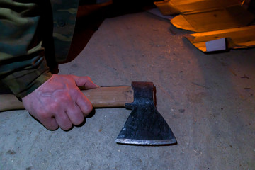 An axe in a worker's man's hand near a campfire.