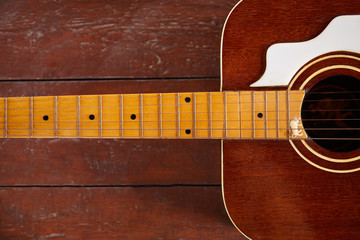 a wooden guitar is lying on a wooden table. The guitar strings are arranged horizontally