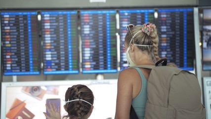 Woman and child baby tourist caucasian at airport with wearing protective medical mask. Family in...