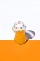 vertical view glass with orange juice on white and orange background