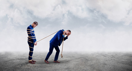 Upset businessman pulls tied himself with a rope.