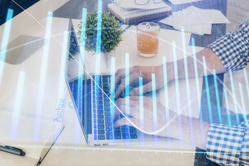 Multi exposure of graph with man typing on computer in office on background. Concept of hard work. Closeup.