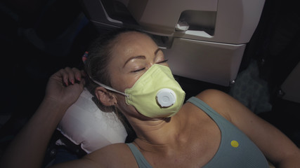 Woman travel caucasian at plane with wearing protective medical mask. Girl tourist at aircraft with...