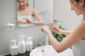 Female taking care of her skin and using moisturizing and nourishing hand cream after bath at home. Skin care product