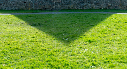 Obraz premium A close up view of the shadow of the church building on the grass in the open park next door to it