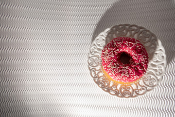 Pink Doughnut in a Vintage White Plate on a White Bakground