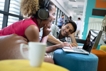 businesspeople working while sitting on beanbag chairs in office. Men using laptops. discussion creative ideas