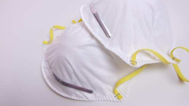 White face masks with N95 particulate filter for virus or dust prevention on white table. Pan right.