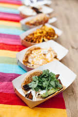 Street food. Many bright tacos in carton boxes on table. Mexican food takeaway. Vegan and healthy.