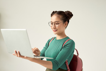 Young happy smiling woman in casual clothes holding laptop and sending email to her best friend