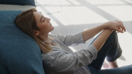 Obraz premium serene attractive young woman resting on couch taking deep breath of fresh air healthy calm lady relaxing on comfortable sofa napping feel stress free at home lounge alone sunlight