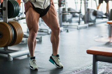 Fototapeta na wymiar Male muscular athlete bodybuilder show thigh muscles.