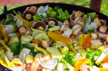 Grilled vegetables close-up  in a cast iron skillet on the grill are cooked on fire, the concept of...